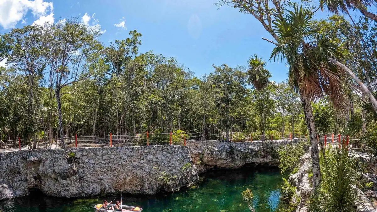 Swimmers in life jackets on the wooden stairs of a semi-open cave cenote on a Casa Tortuga cenote tour near Tulum